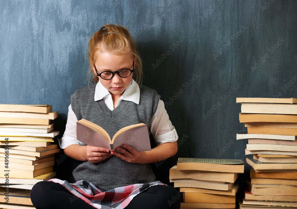 She reads whenever the chance arises. A cute blonde girl reading in class during break surrounded by