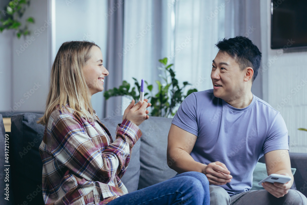 不同种族的男女幸福的夫妇为怀孕测试结果而高兴，年轻的家庭在h