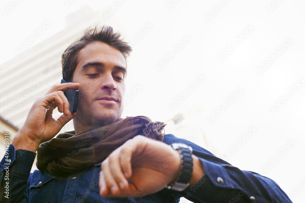 Hes always got some time..... Low angle shot of a man chekcing his watch while talking on his cellph