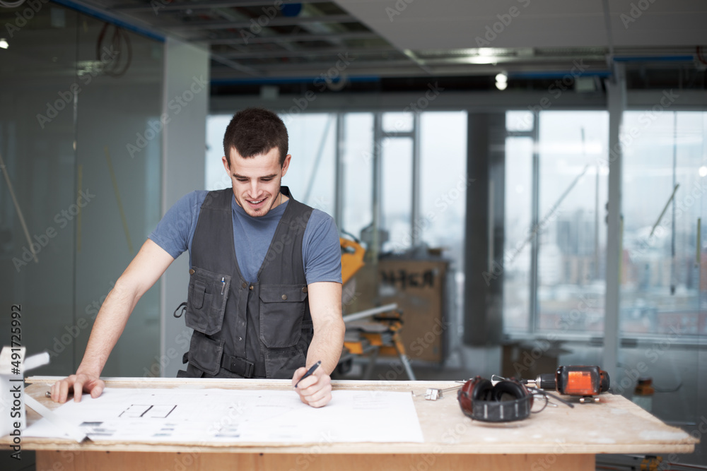 Making some quick changes. Young architect working on his plans while at a construction site.