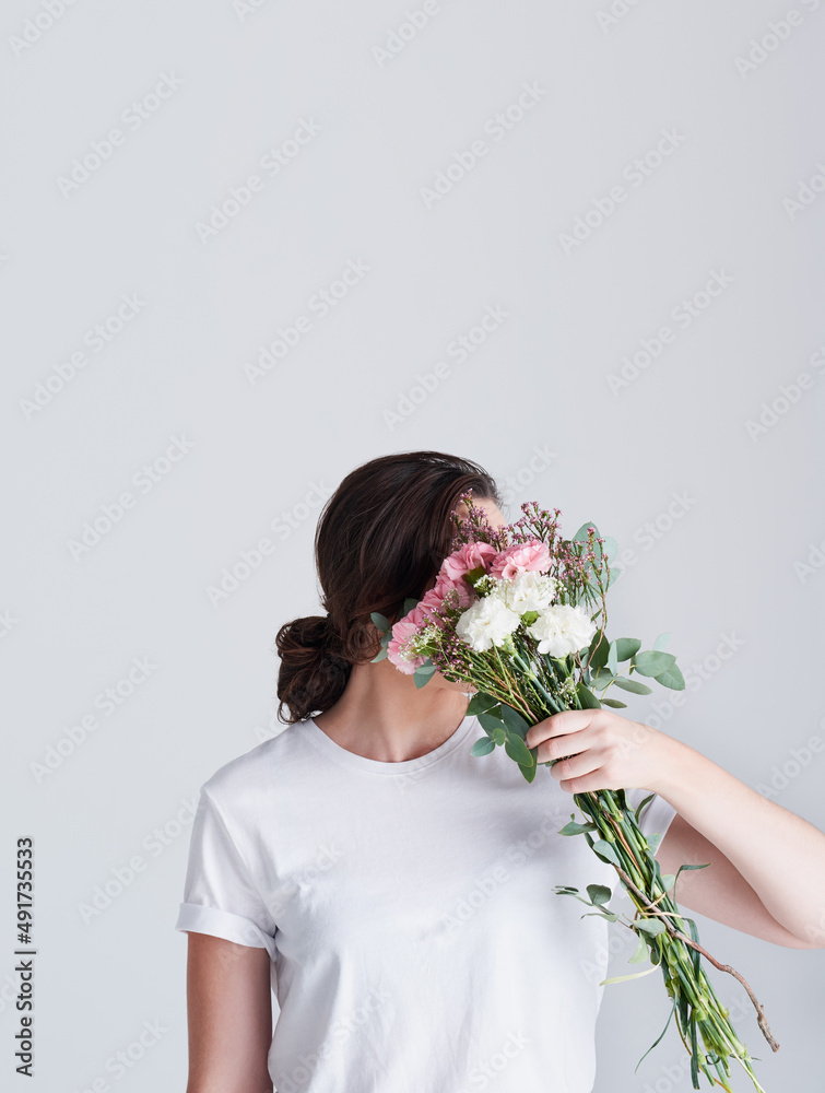 鲜花中有纯洁。一个面目全非的女人用鲜花遮住脸的工作室镜头。