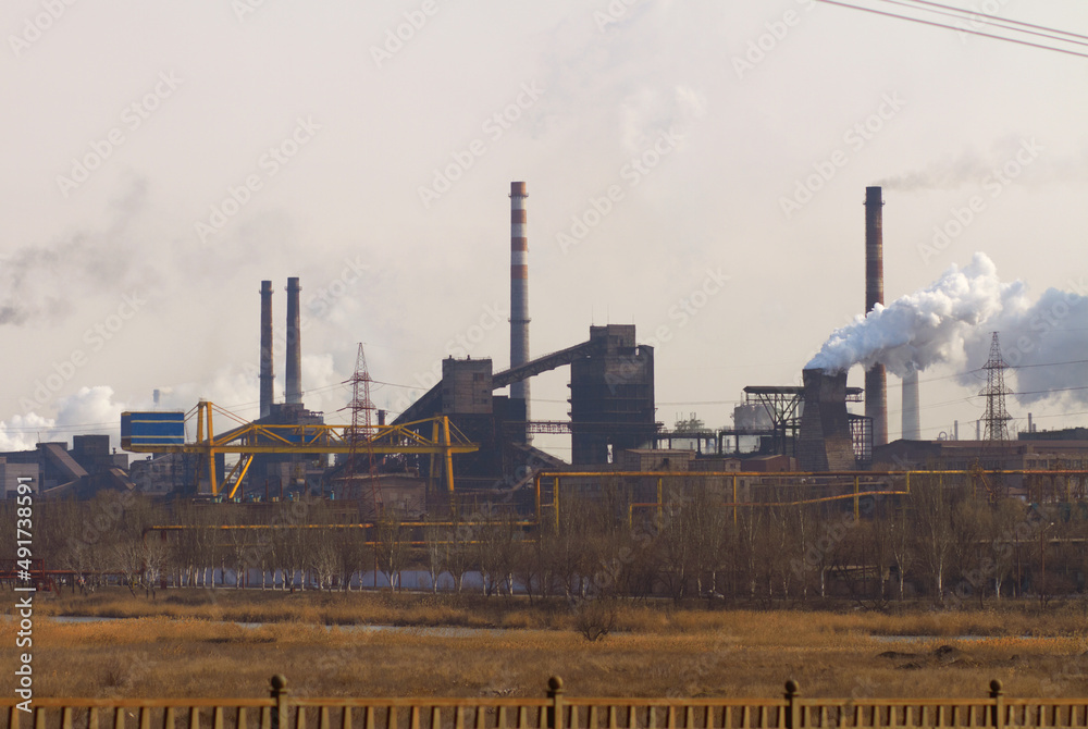 Polluting the air one cloud at a time. Shot of air pollution over an industrial area.