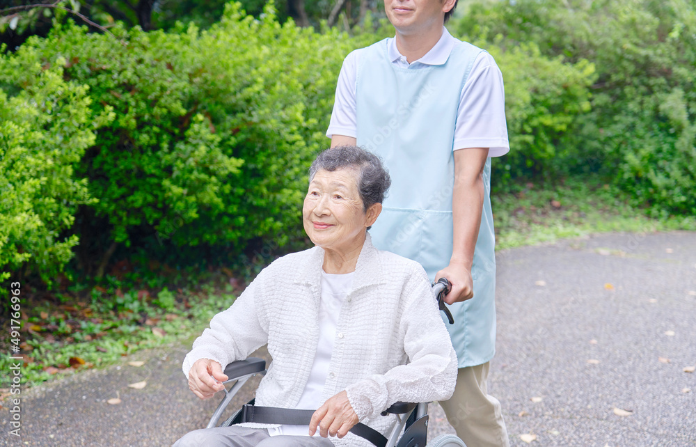 車椅子に乗った高齢者と介護士　屋外