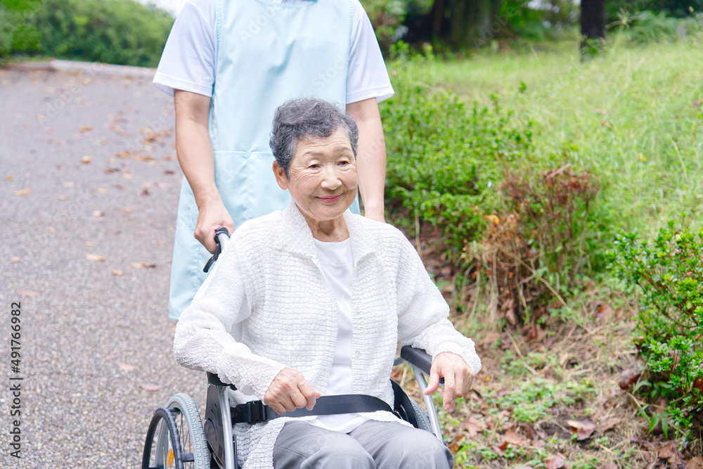 車椅子に乗った高齢者と介護士　屋外