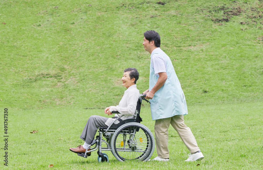 車椅子に乗った高齢者と介護士　屋外