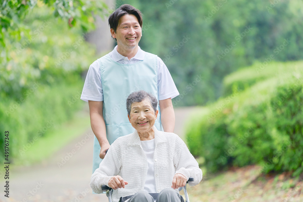 車椅子に乗った高齢者と介護士　屋外