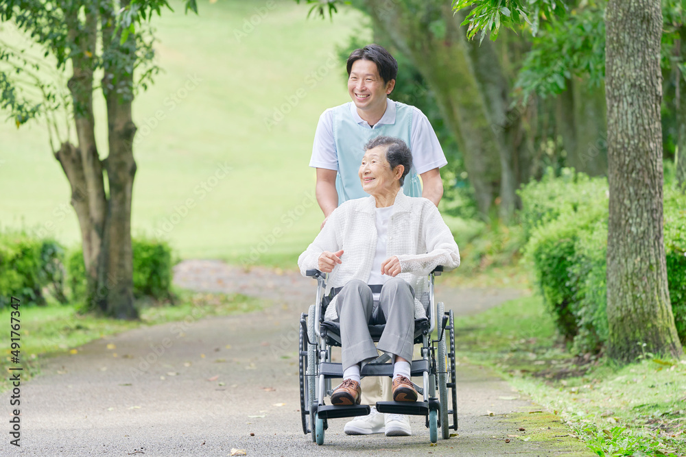 車椅子に乗った高齢者と介護士　屋外