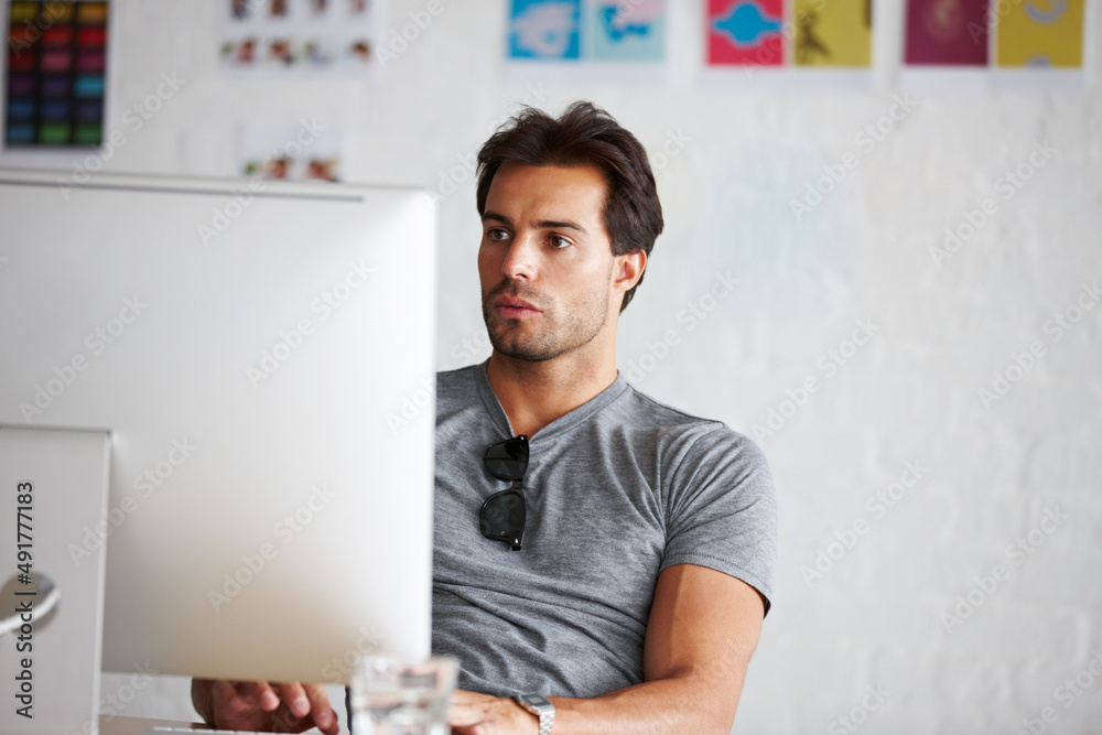 Doing work online. A handsome young man sitting in front of his computer.