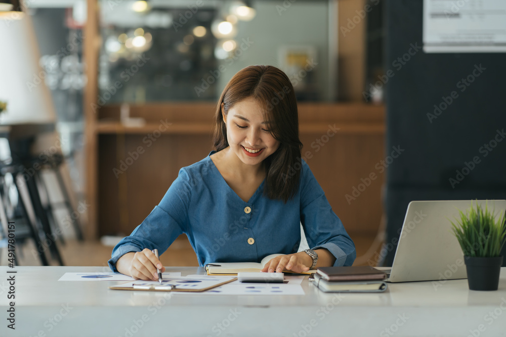 亚洲女商人在木制桌子上用计算器和笔记本电脑做数学金融，