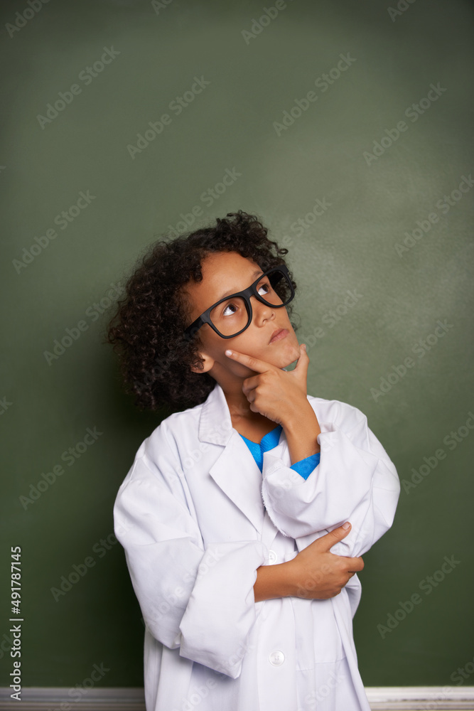 Dreaming of his bright future. An ethnic boy wearing glasses and a lab coat looking contemplative - 