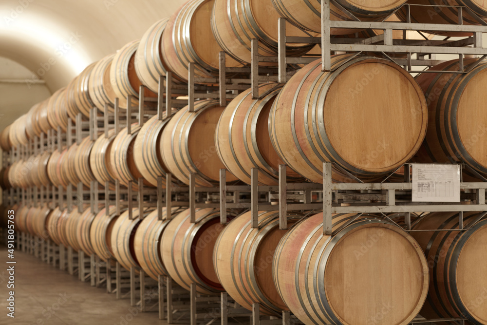 Mass producing wine. Stacked barrels of wine at a wine distillery.