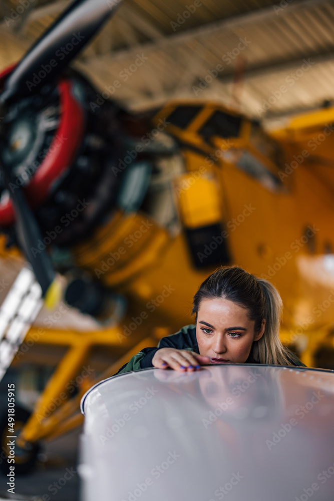 Distant shot of female caucasian pilot, scrubbing the plane clea