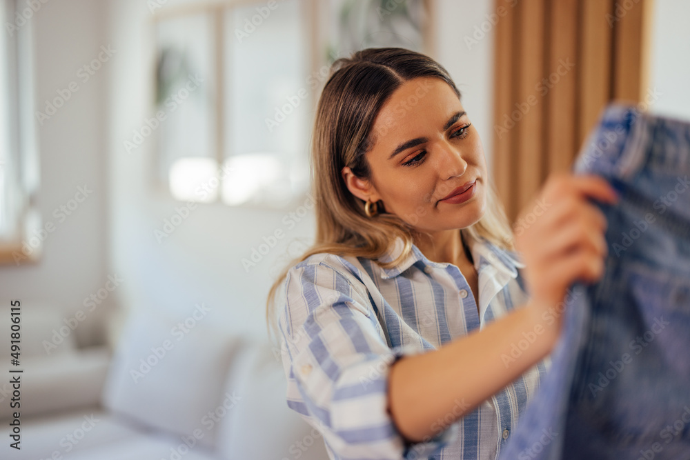 Young female, thinking about those jeans, doing the packing for travel.