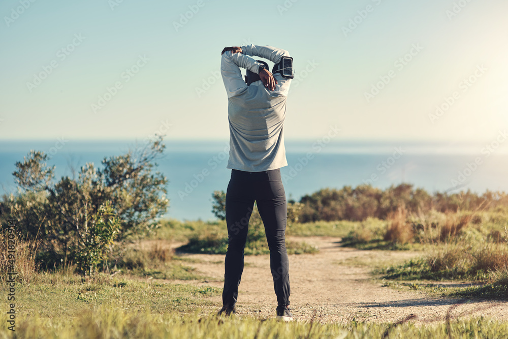 Preparation is key. Rearview shot of an unrecognizable young man stretching before exercising outdoo