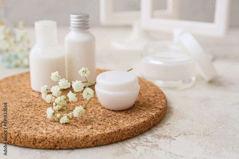 Cork mat with cosmetic products and gypsophila flowers on table, closeup