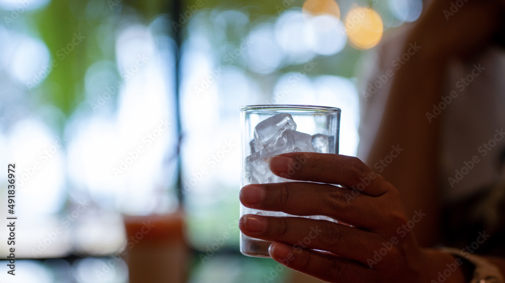 Woman hand holding ice in glass in the shop or restaurant