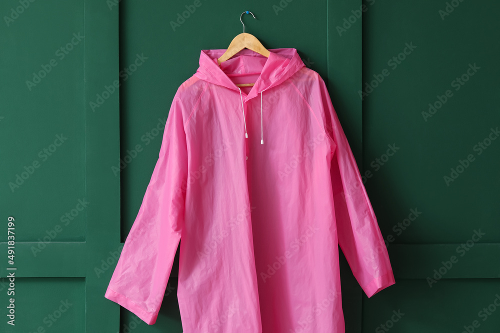 Raincoat hanging on green wall