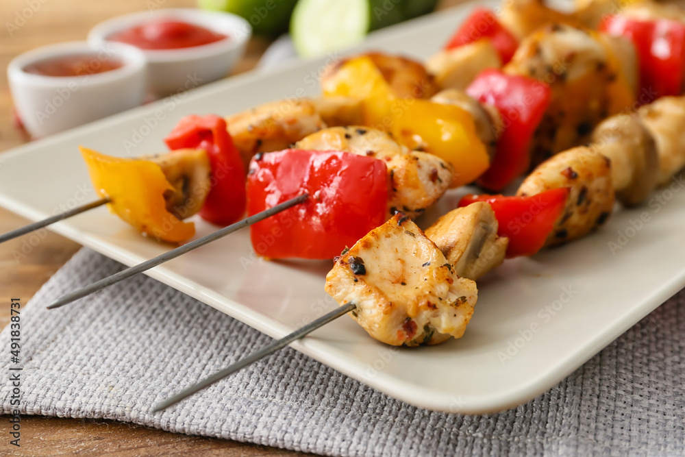 Plate of grilled chicken skewers with vegetables on table, closeup