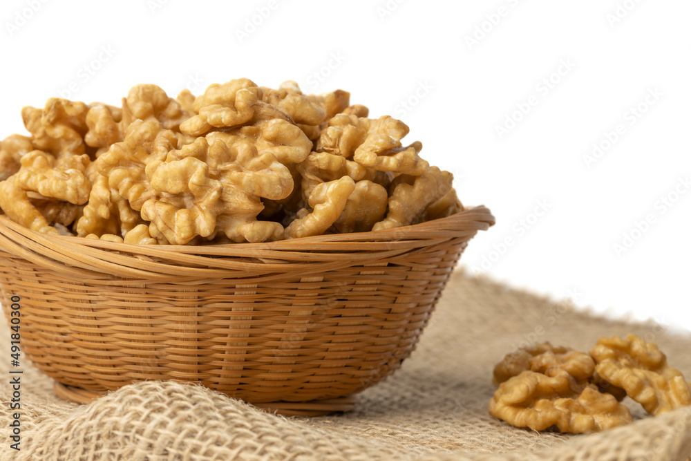 Peeled walnut in a basket on a burlap isolated on white background.