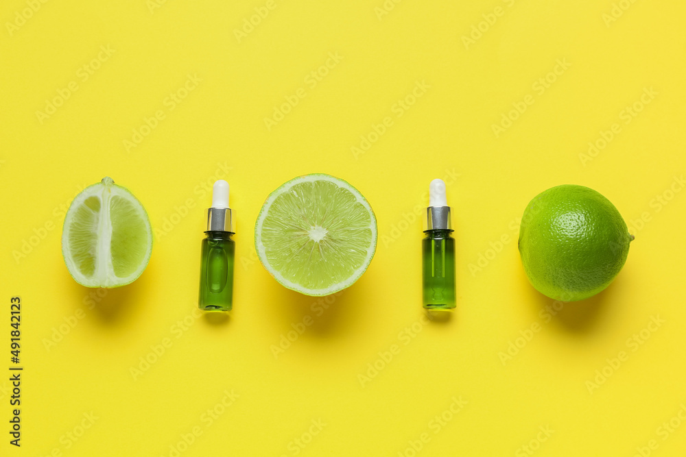 Bottles of essential oil and bergamot fruits on yellow background