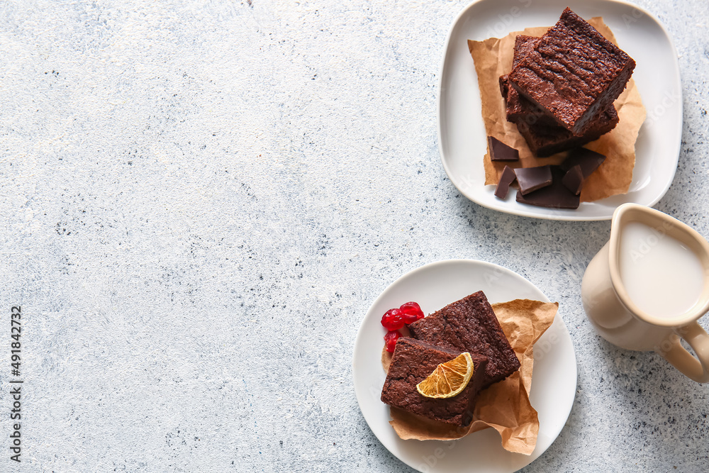 Plates with pieces of delicious chocolate brownie on light background