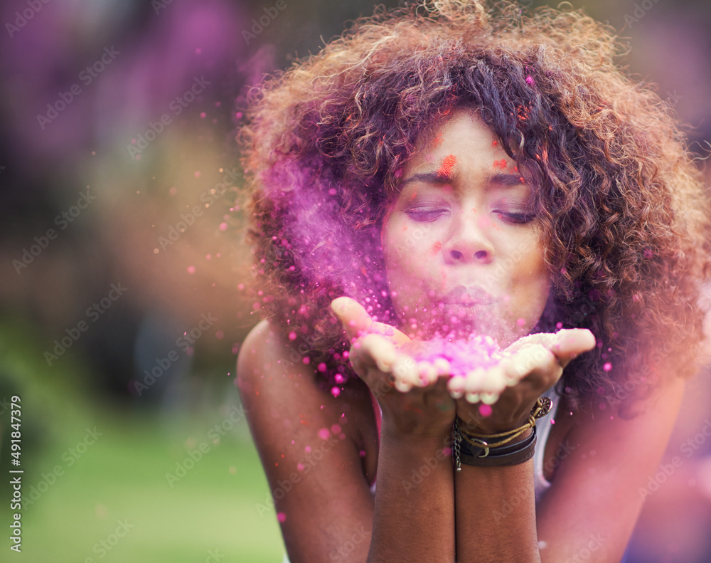 Painting the world pink. Shot of an attractive young woman blowing purple paint powder at the camera