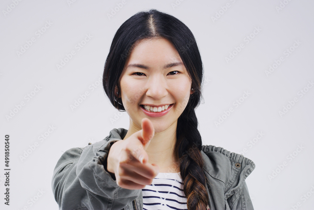 Youre the chosen one. Portrait of a beautiful young woman pointing to the camera against a grey back