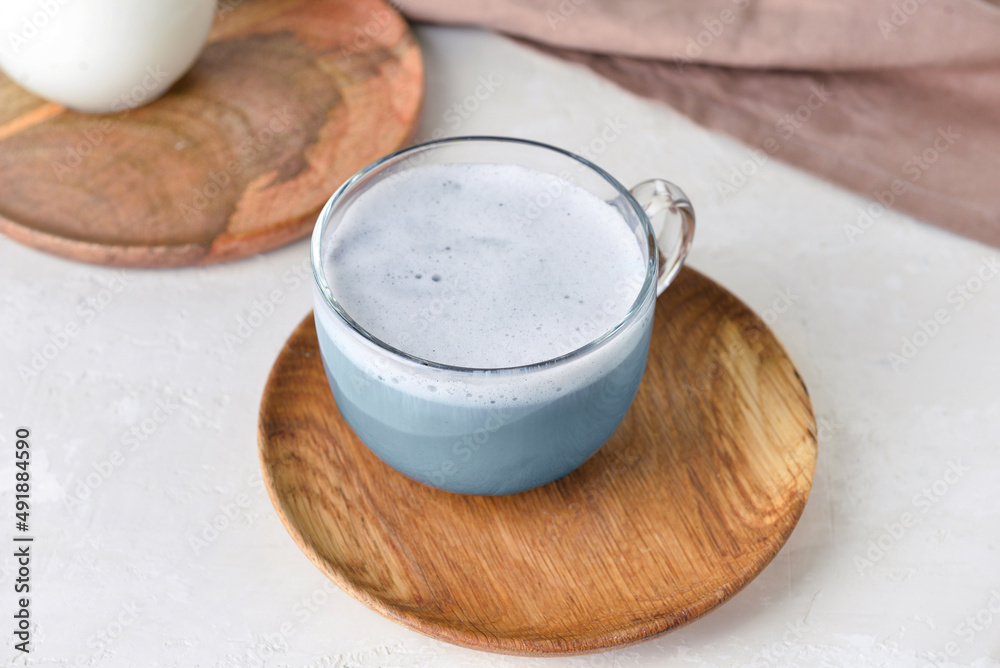 Wooden plate with glass cup of delicious Charcoal Latte on light table