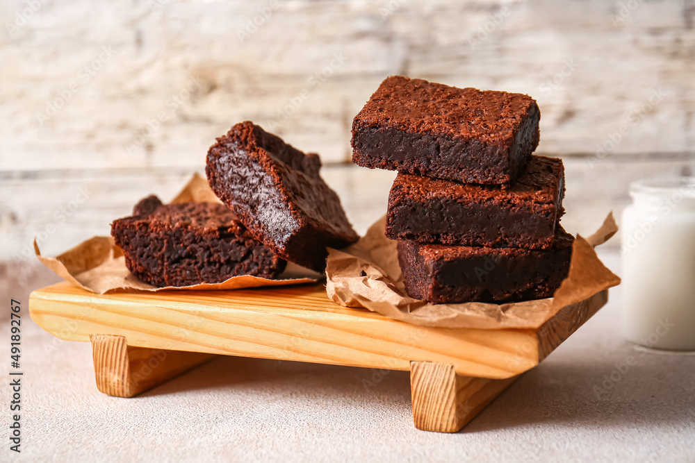 Wooden board with pieces of delicious chocolate brownie on table