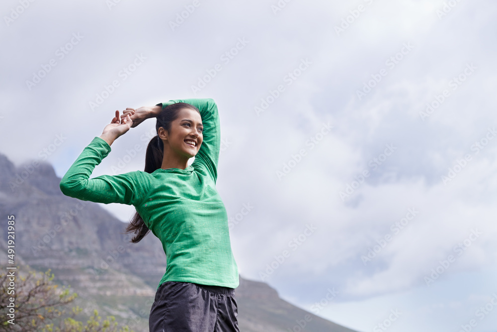 从顶部欣赏风景。一位年轻的少数民族妇女一边伸展身体，一边从顶部观看风景