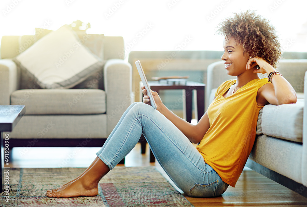 Catching up with life online on her day off. Shot of a young woman using a digital tablet on a relax