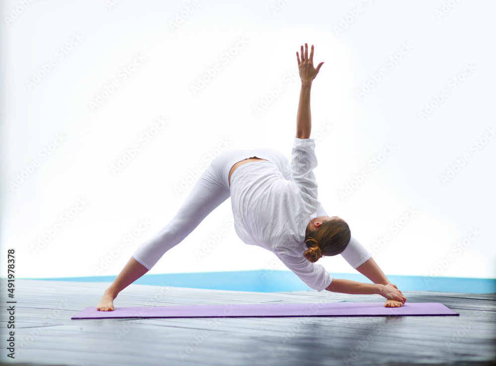 Demonstrating a perfect triangle pose. Shot of a gorgeous young woman doing yoga outdoors beside a p