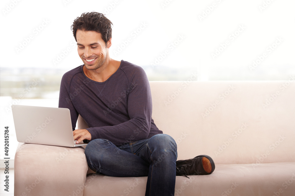 I learn something new every day. Portrait of a handsome young man using his laptop at home.