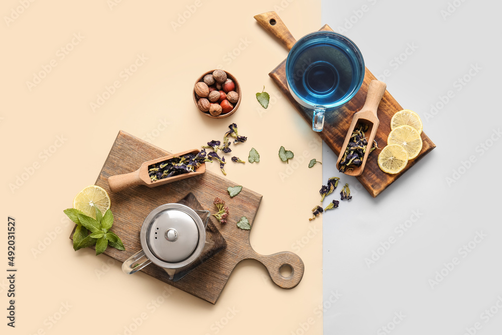 Composition with cup of blue tea, nuts and dried butterfly pea flowers on color background