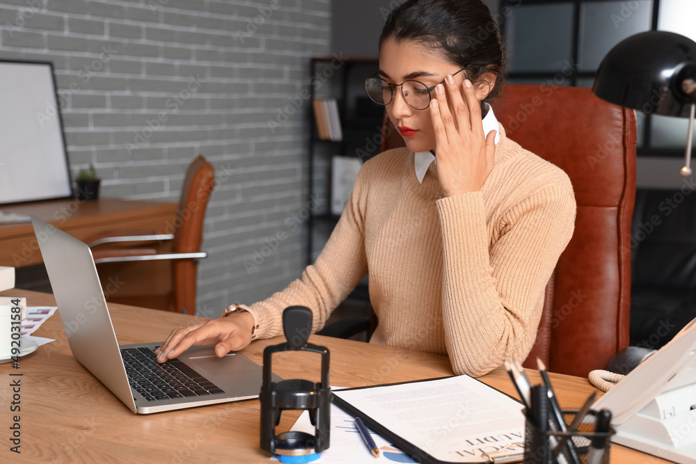 Female notary public working on laptop in office