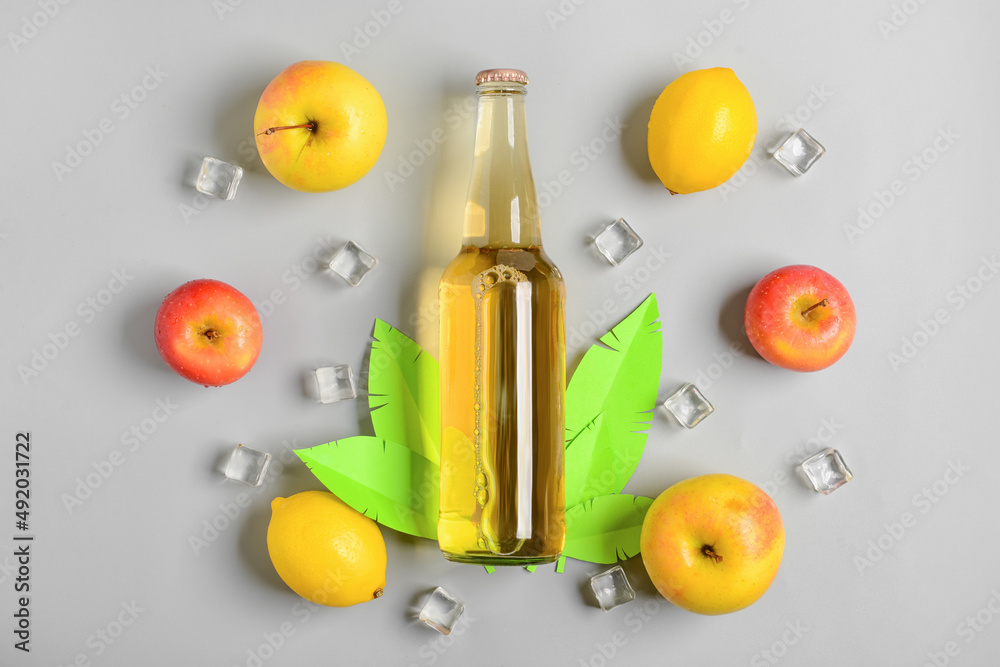 Composition with bottle of fresh soda, apples and ice cubes on grey background