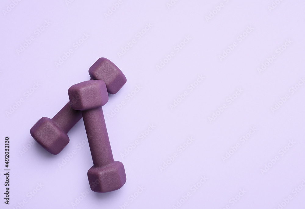 Stylish dumbbells on purple background