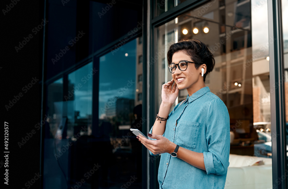 音乐帮助我等待。一个漂亮女人站在外面戴上耳机的裁剪镜头