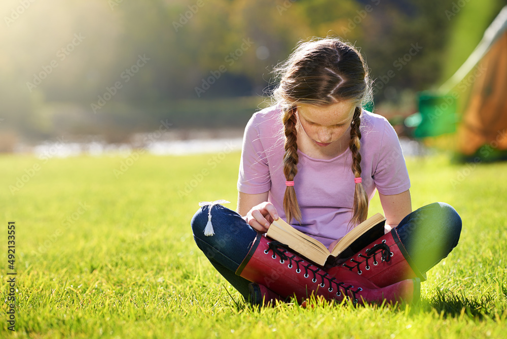 Keep learning all summer long. Shot of a teenage girl relaxing with a book on the grass.