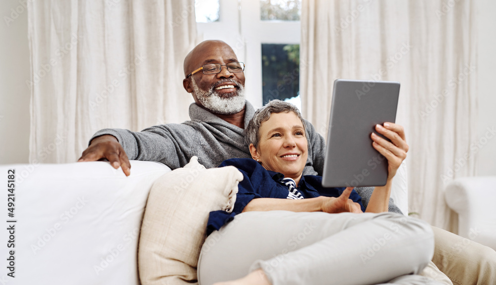 Spending the day together at home. Shot of an affectionate senior couple using a tablet while relaxi