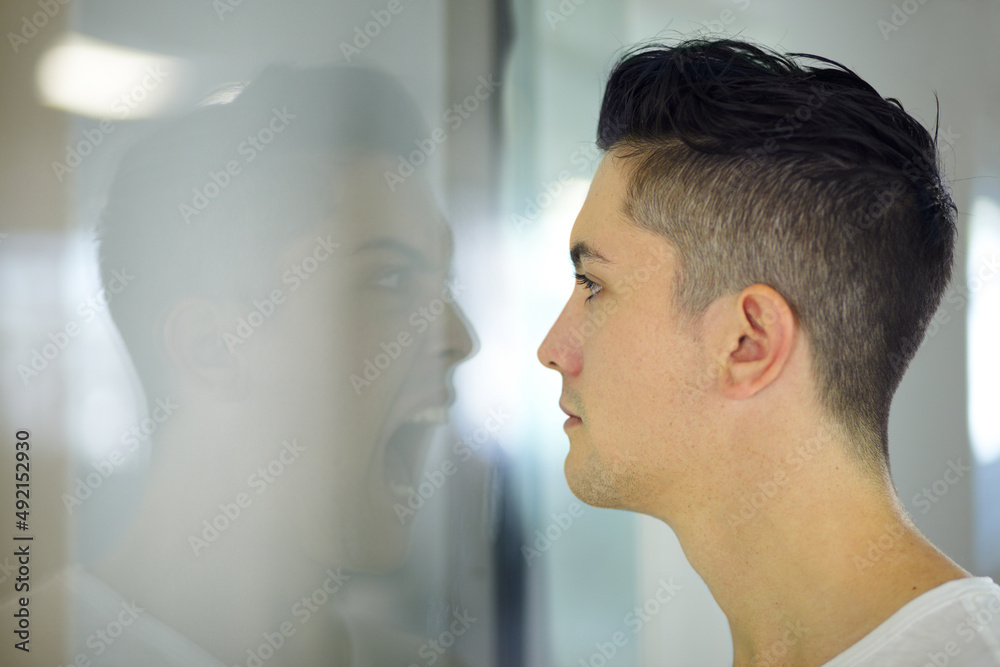 Screaming inside. Young man looking at a screaming reflection of himself.