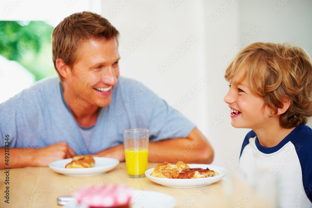 Cheerful father and son together having breakfast. Portrait of a cheerful father and son together ha