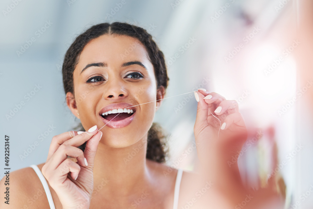 Brushing alone simply wont do it. Cropped shot of an attractive young woman flossing her teeth in th