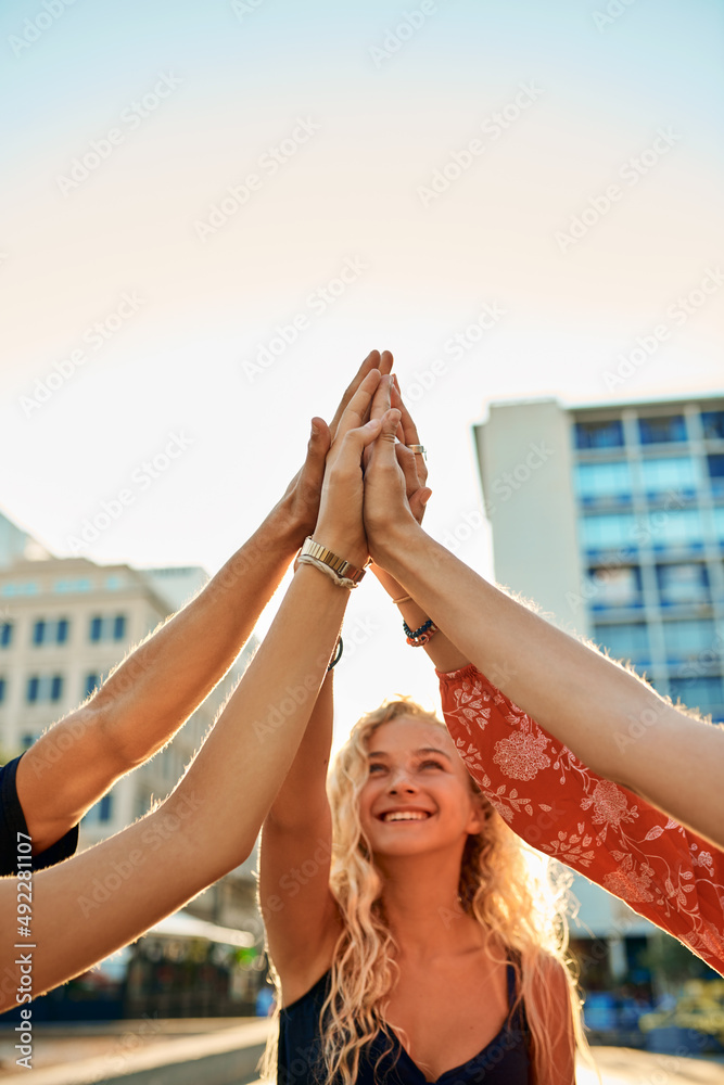 The city is ours. Cropped shot of a group of young friends high fiving while out in the city.