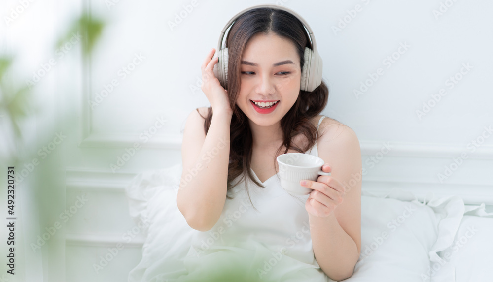 Image of young Asian woman listening music at home in the morning