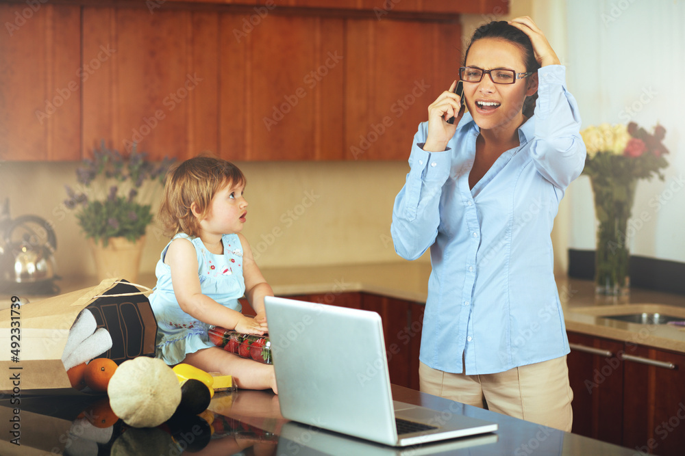 Juggling work and family leaves her frazzled and frustrated. Shot of a busy young mother at home wit