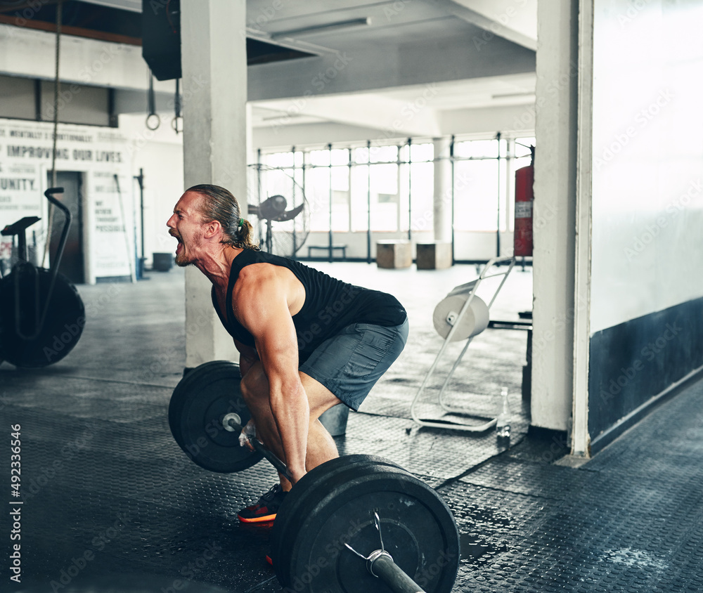 Sore. The most satisfying pain. Shot of a man lifting weights at the gym.