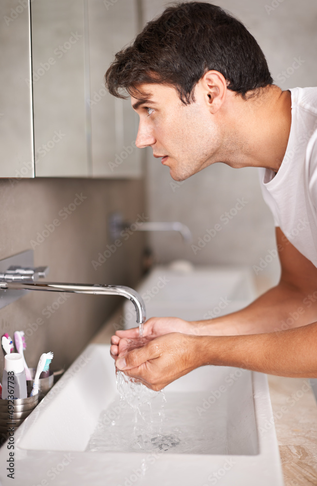 Getting his morning routine out of the way. Shot of a man looking in the mirror while holding his ha