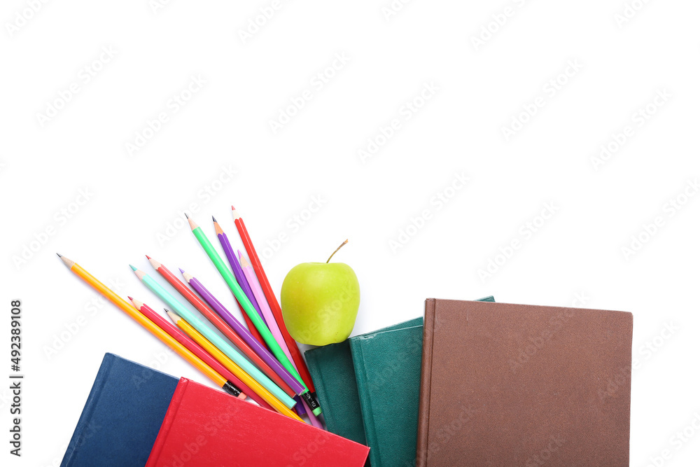 Different notebooks, color pencils and apple on white background