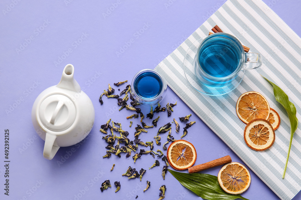 Composition with cups of blue tea, dried fruits and butterfly pea flowers on color background